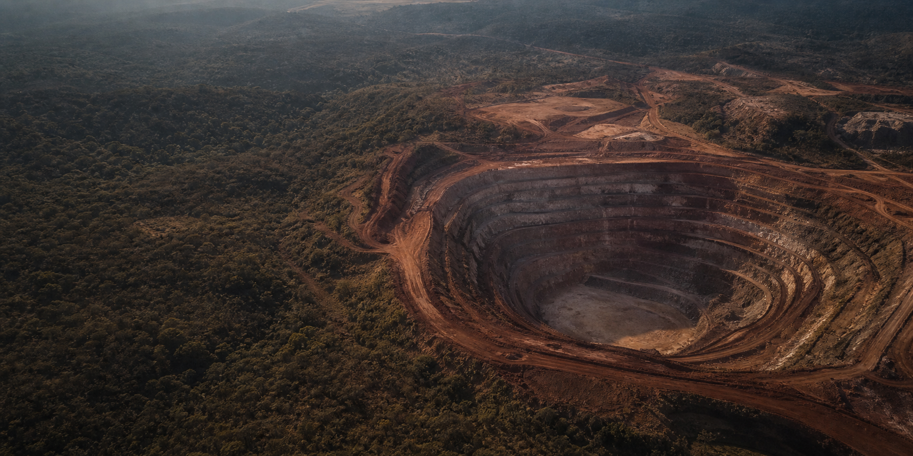 Vista aérea oblíqua de uma cava de ouro entre solo laterítico e vegetação de Cerrado